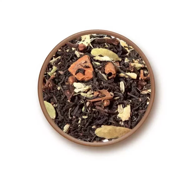 Mélange de thé Chai avec feuilles de thé noires, morceaux de cannelle et cardamome dans un bol en terre cuite.