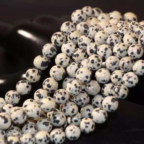 Amas de perles en Jaspe Dalmatien polies sur fond noir, parfait pour les artisans de bijoux